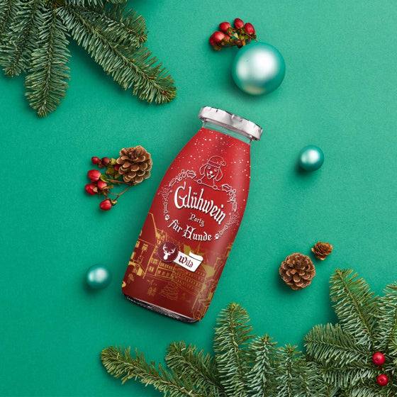 SmoothieDog® Winter Edition Wild, 250 ml, umgeben von weihnachtlicher Dekoration auf grünem Hintergrund.