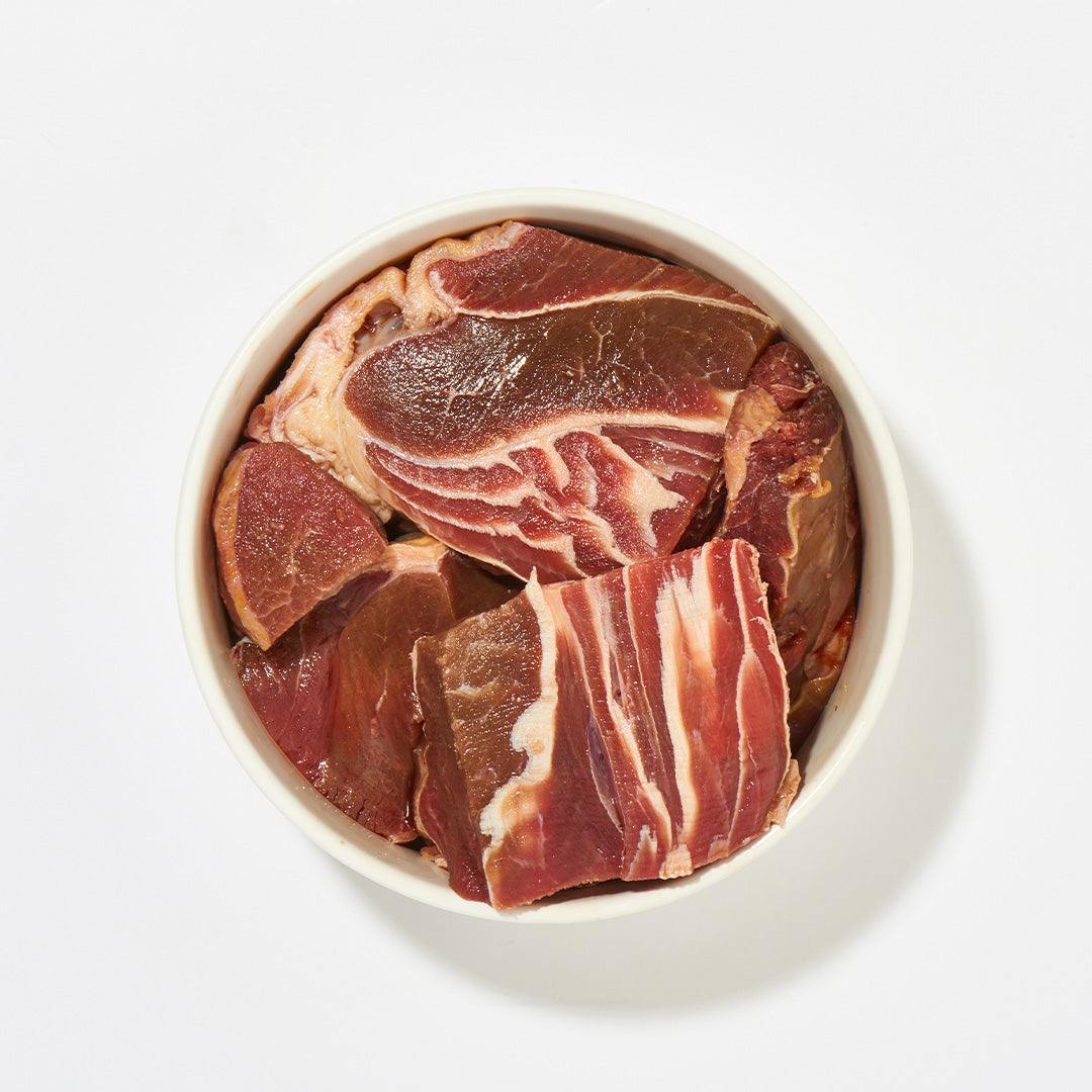 Rindfleisch-Klumpen in einer Schüssel, 2 kg, aus Muskelfleisch mit Fett und Sehnen.