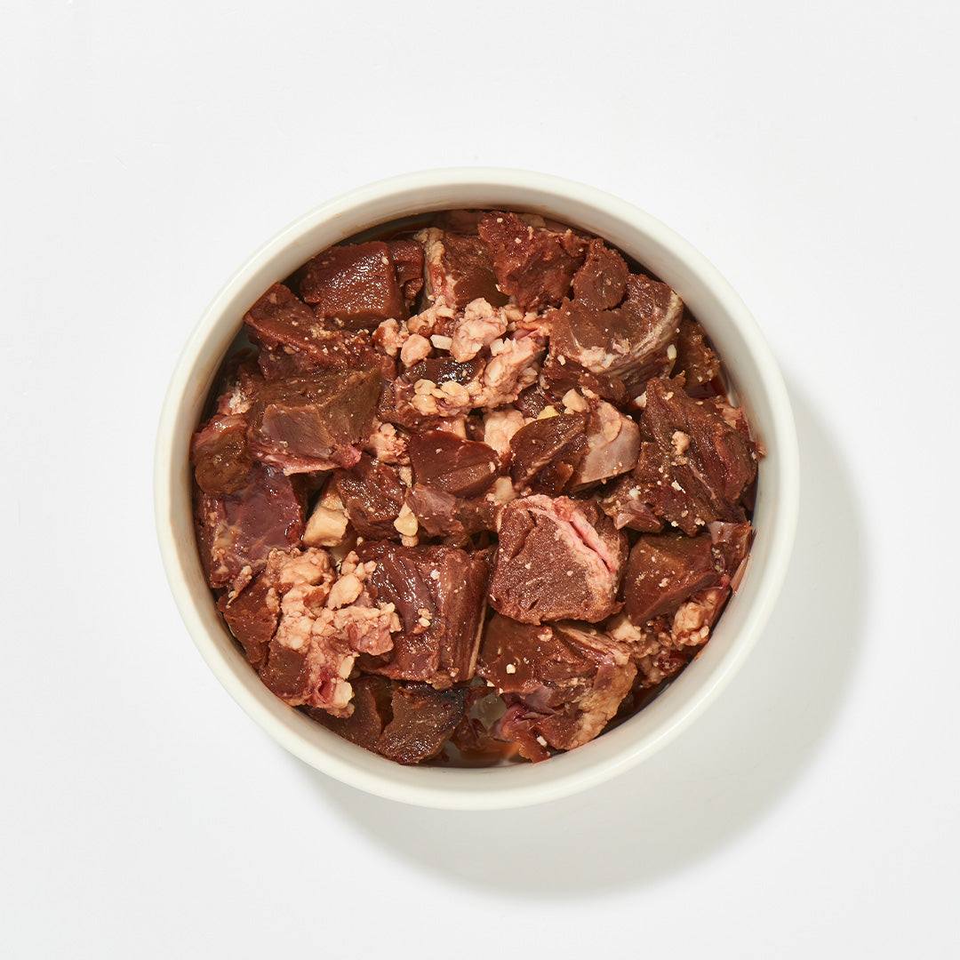 Straußenfleisch in weißem Napf, eiweißreich und fettarm, für Hunde und Katzen jeder Altersgruppe, in Würfeln tiefgekühlt verpackt.