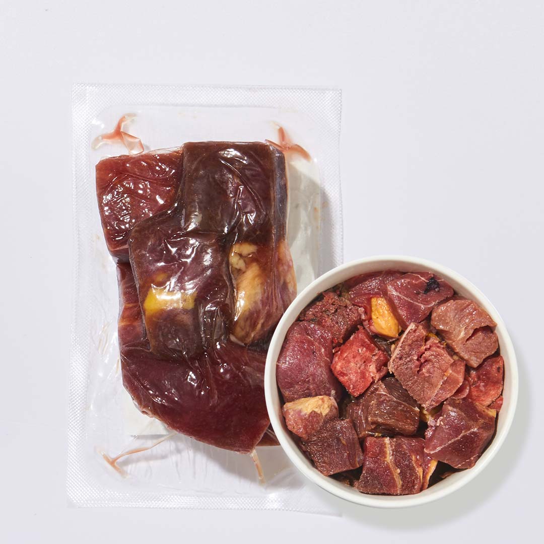 gefüllte vakuumverpackung mit tiefgekühltem pferdefleischgulasch und schale mit gewürfeltem pferdefleisch für hunde und katzen