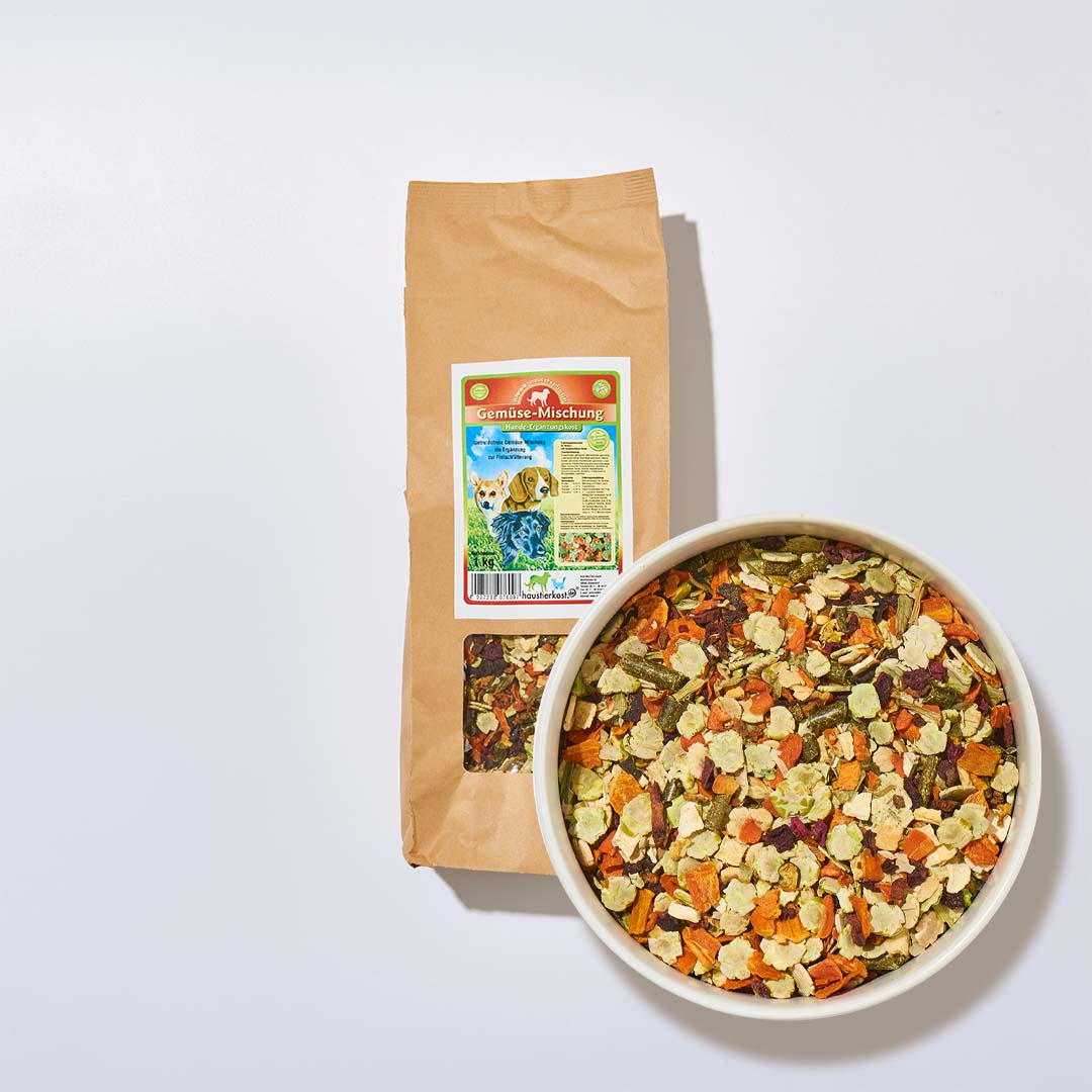 Getreidefreie Gemüse-Mischung 1 kg als Ergänzung zur Fleischfütterung in brauner Verpackung mit bunter Gemüsemischung in weißer Schale