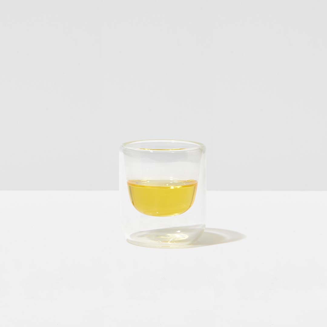 glas mit dorschlebertran in gelber farbe auf weißem hintergrund