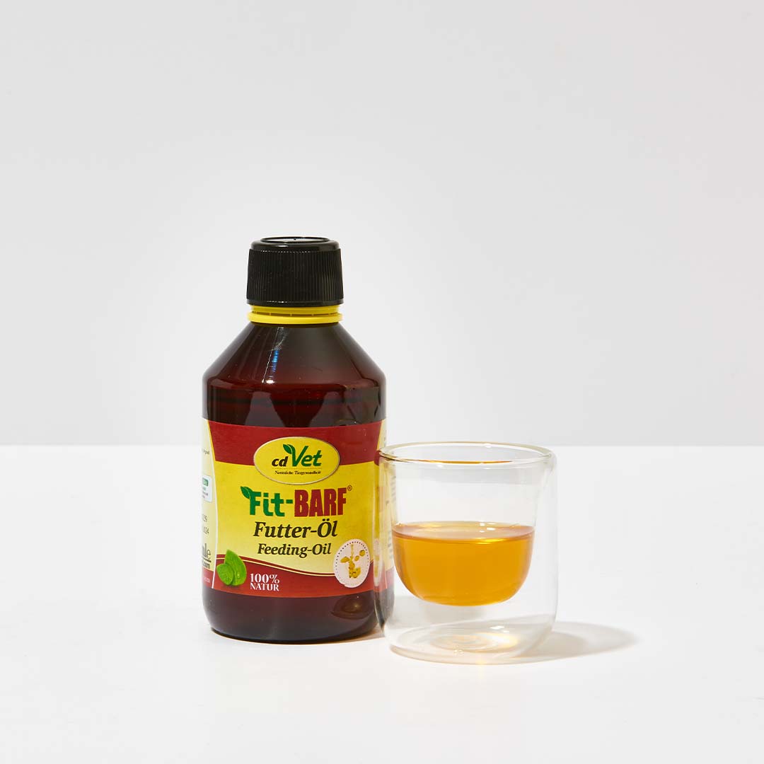 Flasche cdVet Fit-BARF Futter-Öl 250 ml neben Glas mit gelbem Öl, kaltgepresste Pflanzenöle für Haustierernährung