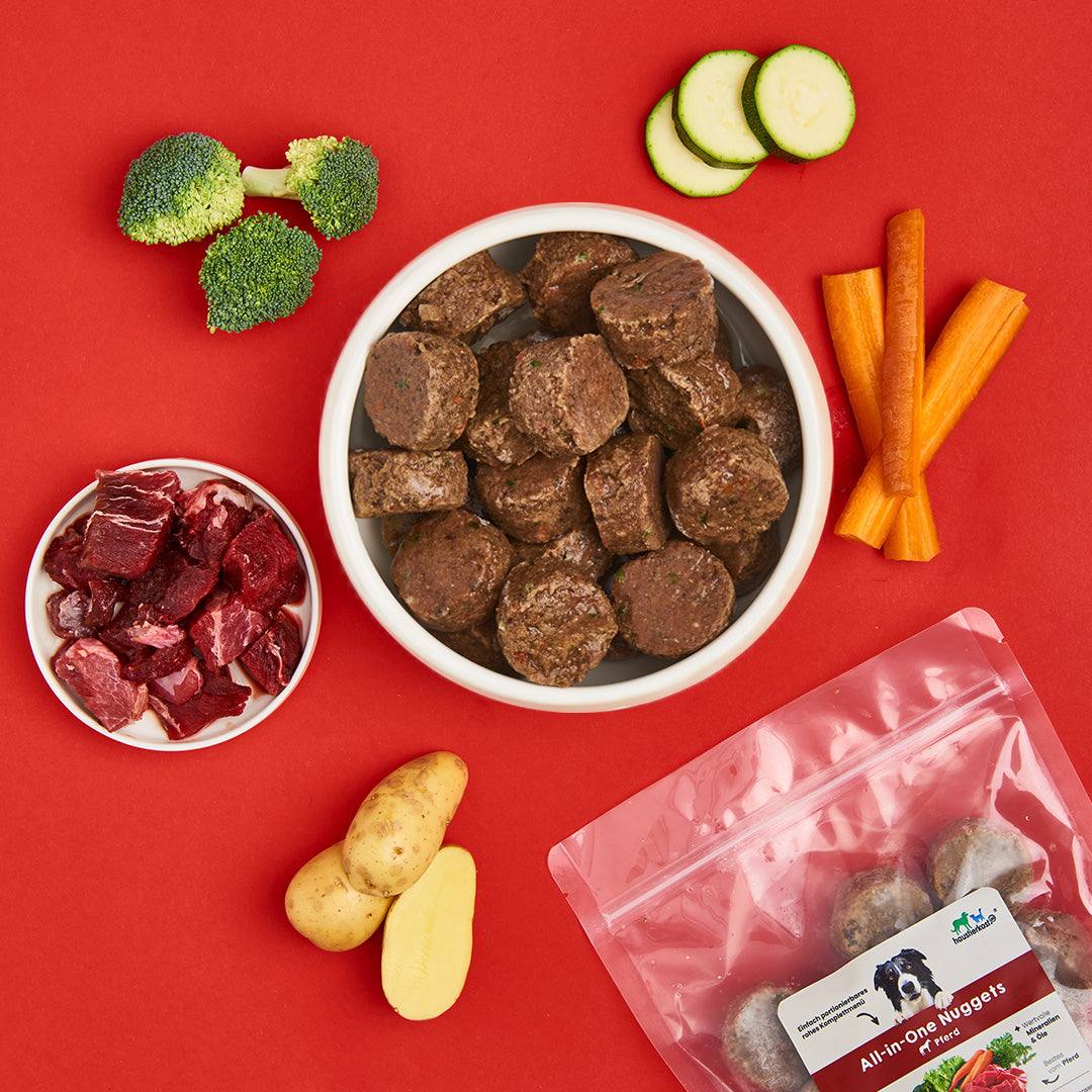 All-in-One Nuggets Pferd für Hunde, mit Gemüse und Fleisch auf rotem Hintergrund.
