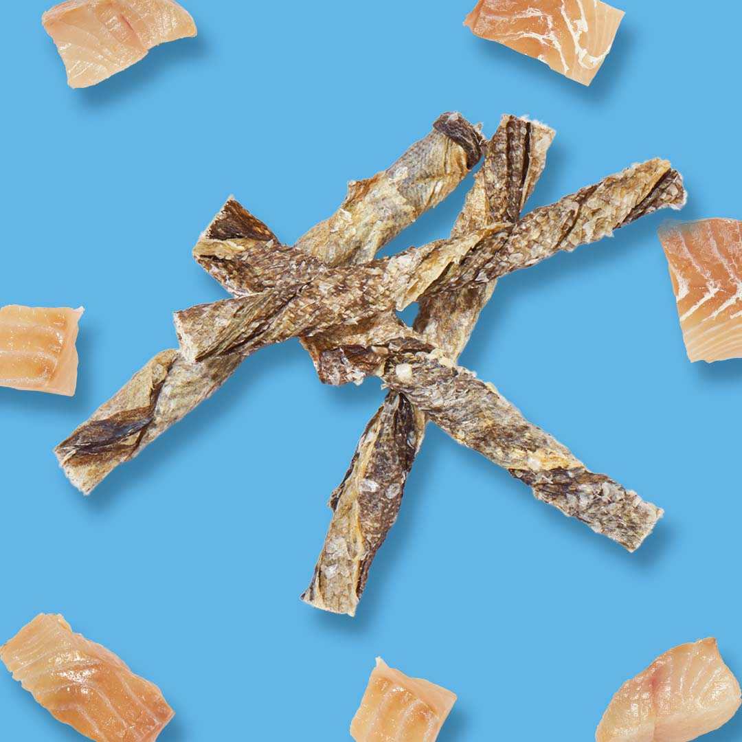 Kabeljau-Kaustangen auf blauem Hintergrund, umgeben von kleinen Fischstücken.