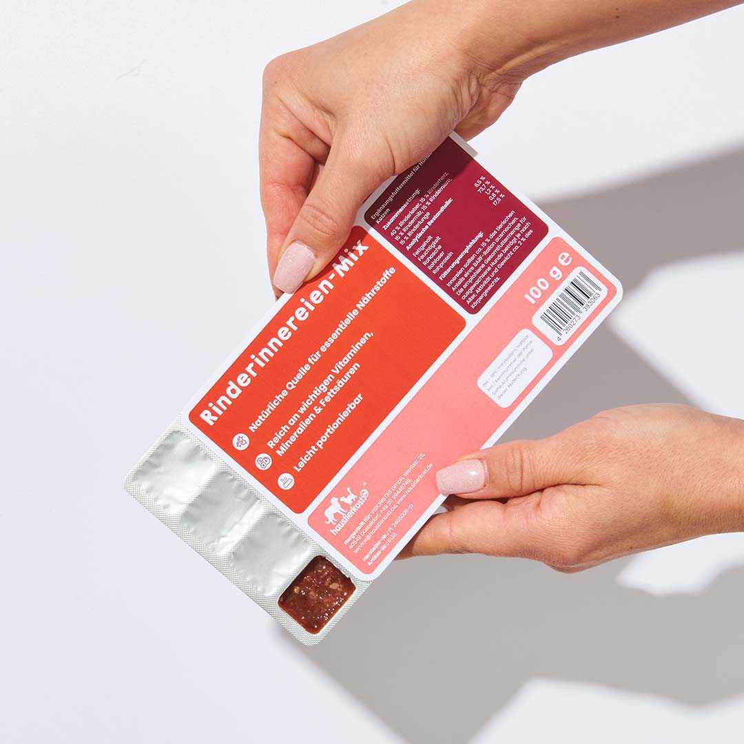 Rinderinnereienmix 100 g im Blister, 20 Würfel à 5 g, Leber, Niere, Herz, Milz, Lunge, nährstoffreiche Ergänzung. Hände halten das Produkt vor weißem Hintergrund.