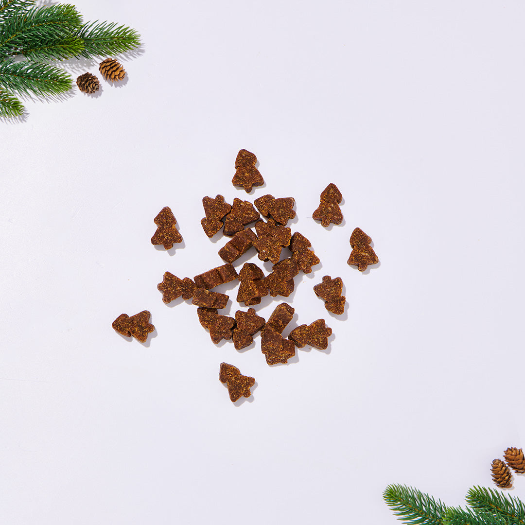 BARF Softies mit Käse in Baumform auf weißem Hintergrund mit Tannenzweigen und Zapfen